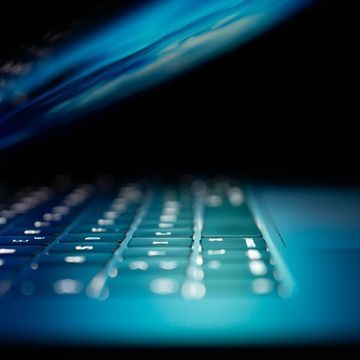 Halb aufgeklappter, blau beleuchteter Laptop