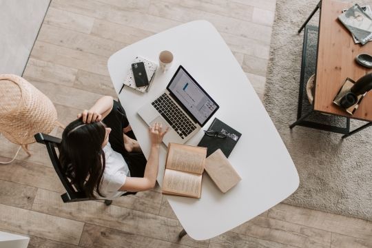 Klicken Sie, um das Bild zu bearbeiten Frau an Schreibtisch mit Laptop und Büchern von oben