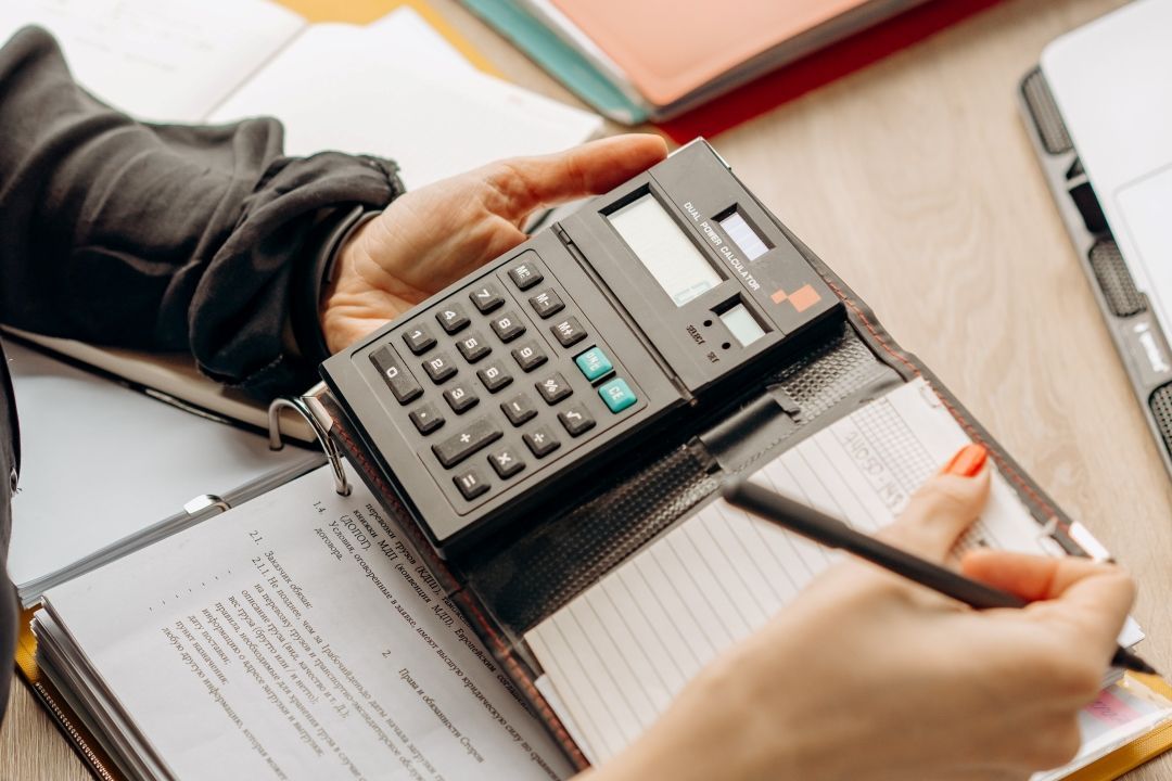 Person hält Taschenrechner und Stift in der Hand