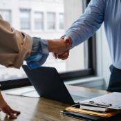 Zwei Personen reichen sich über einen Tisch hinweg die Hand