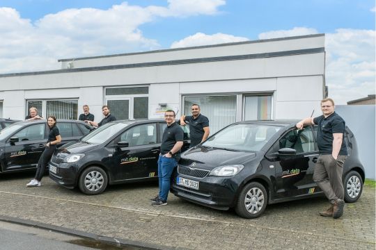 Mitarbeitende vor dem Fuhrpark der mit.data