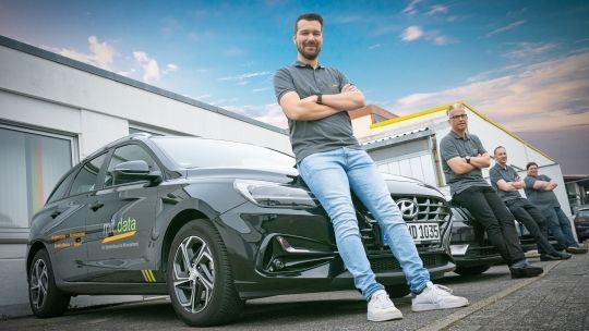 Mitarbeitende vor dem Fuhrpark der mit.data